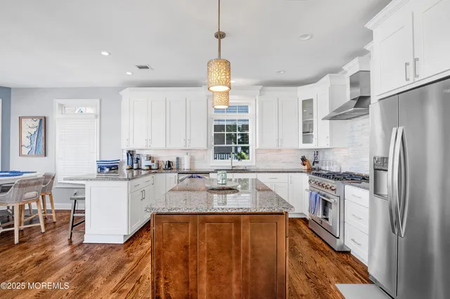 a kitchen with a stove a sink a refrigerator and white cabinets