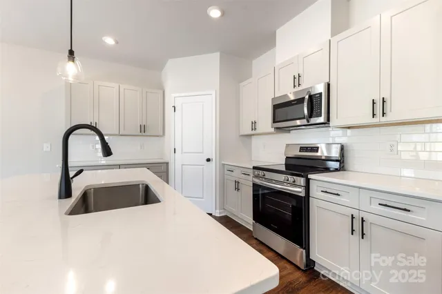 a kitchen with stainless steel appliances granite countertop a sink a stove a microwave and a refrigerator