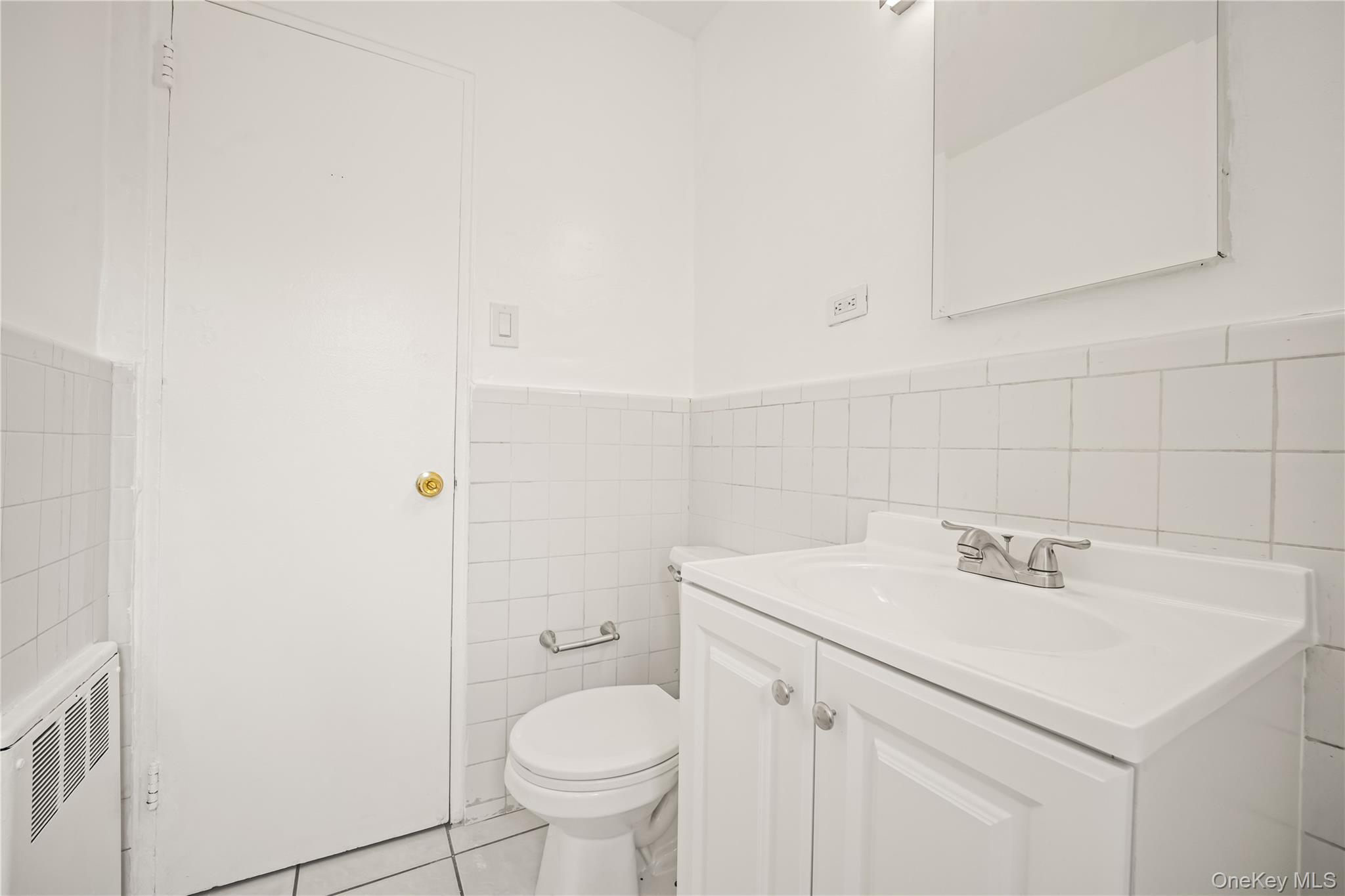 73-10 Springfield Boulevard, Unit B Queens, NY 11364 - Photo 18 of 20 Bathroom featuring vanity, a wainscoted wall, light tile patterned floors, tile walls, and radiator heating unit