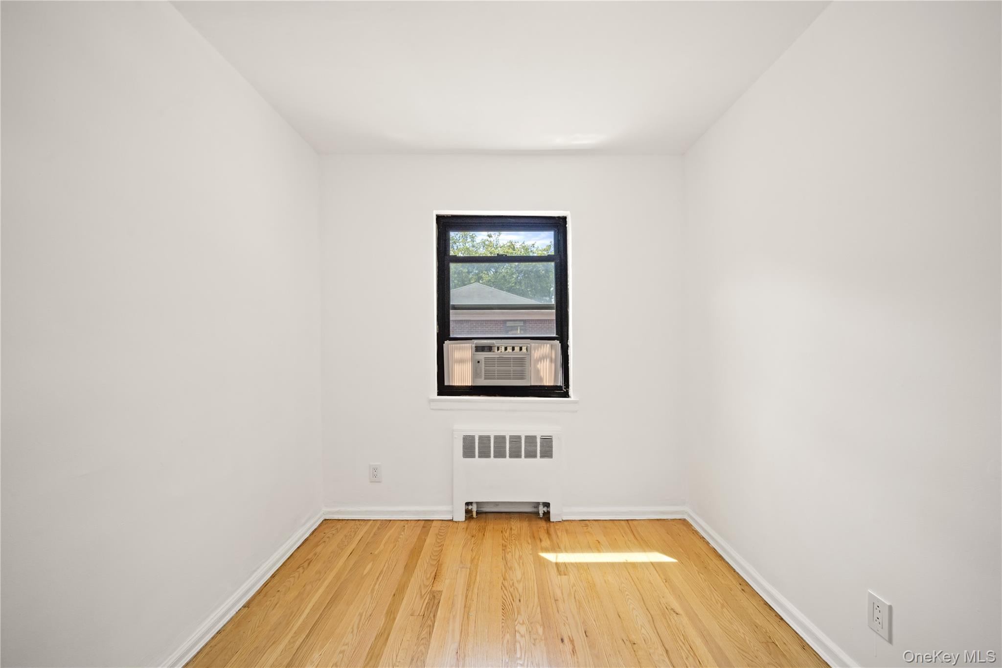 73-10 Springfield Boulevard, Unit B Queens, NY 11364 - Photo 2 of 20 Unfurnished room with light wood-style floors and radiator heating unit