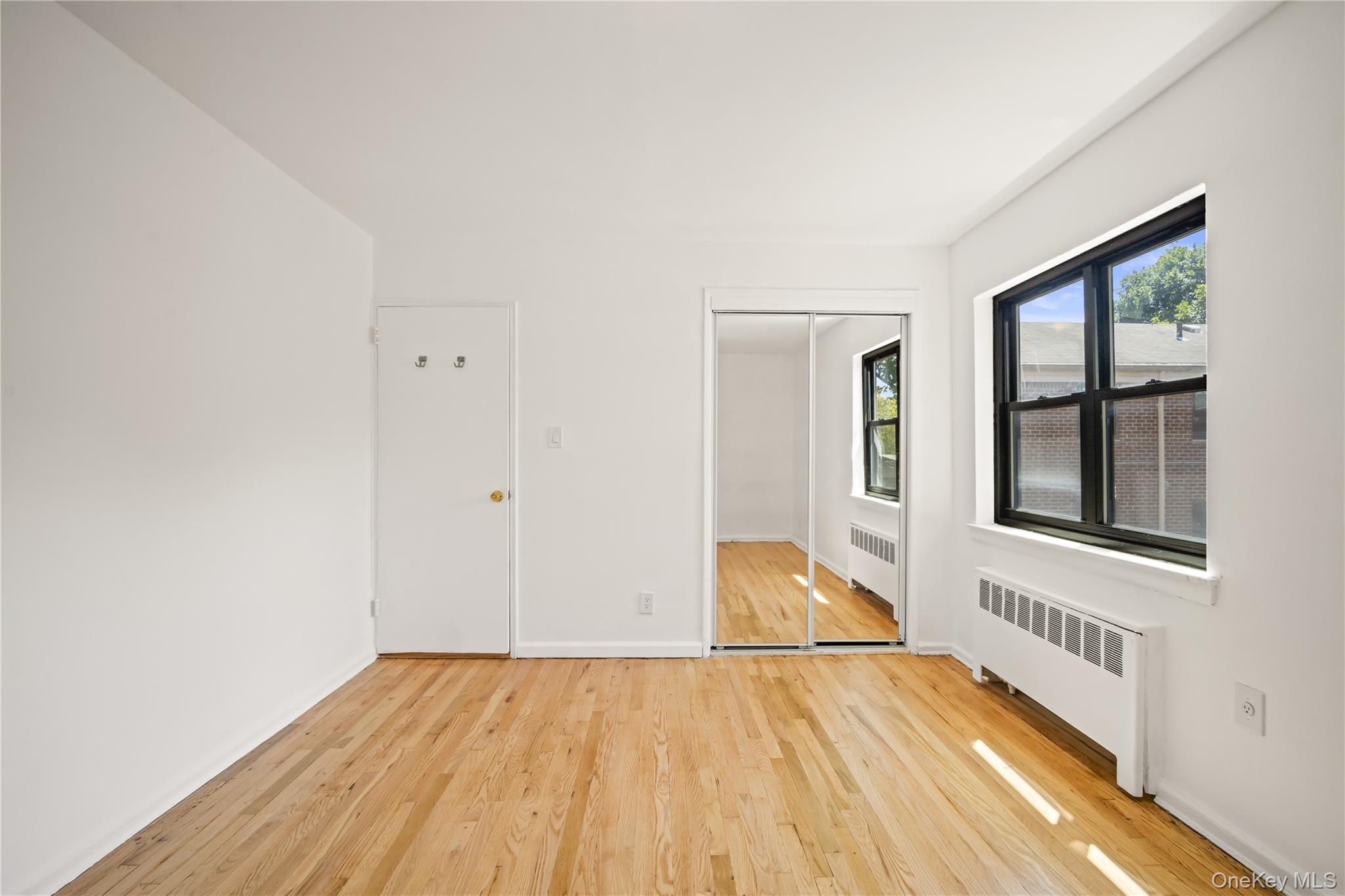 73-10 Springfield Boulevard, Unit B Queens, NY 11364 - Photo 3 of 20 Spare room with light wood finished floors and radiator