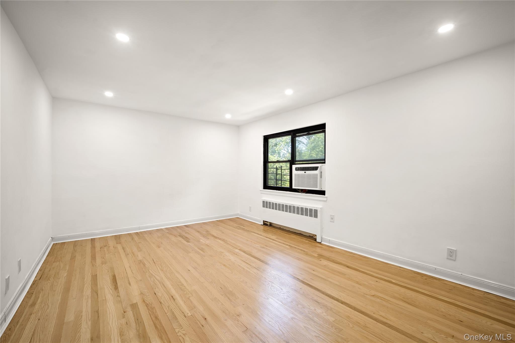 73-10 Springfield Boulevard, Unit B Queens, NY 11364 - Photo 4 of 20 Spare room with recessed lighting, light wood finished floors, and radiator