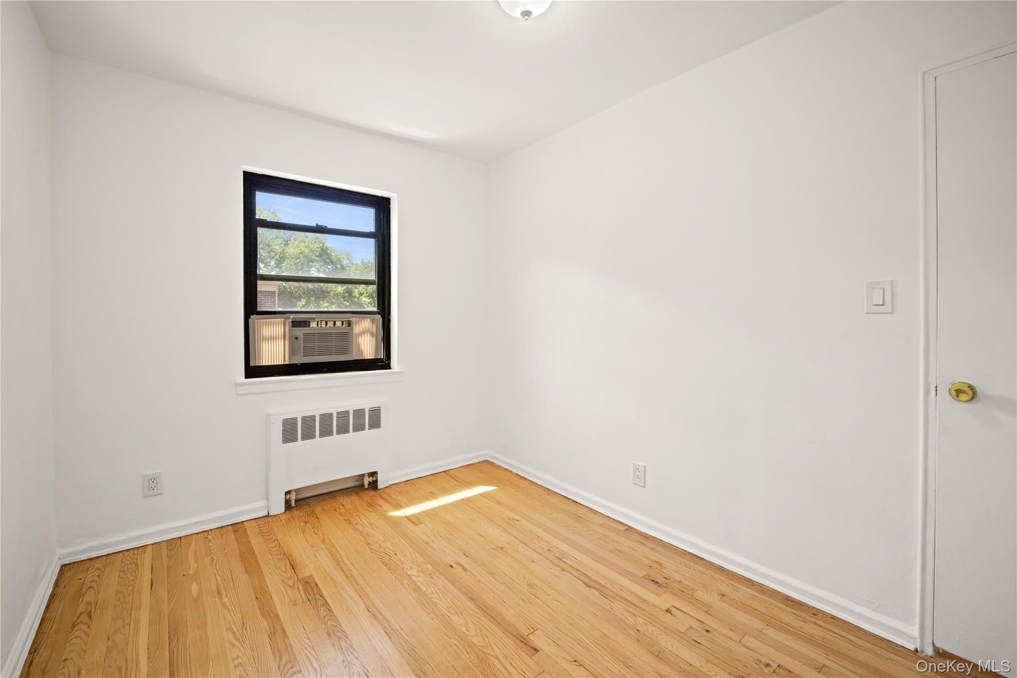 73-10 Springfield Boulevard, Unit B Queens, NY 11364 - Photo 7 of 20 Spare room featuring radiator and light wood-style floors