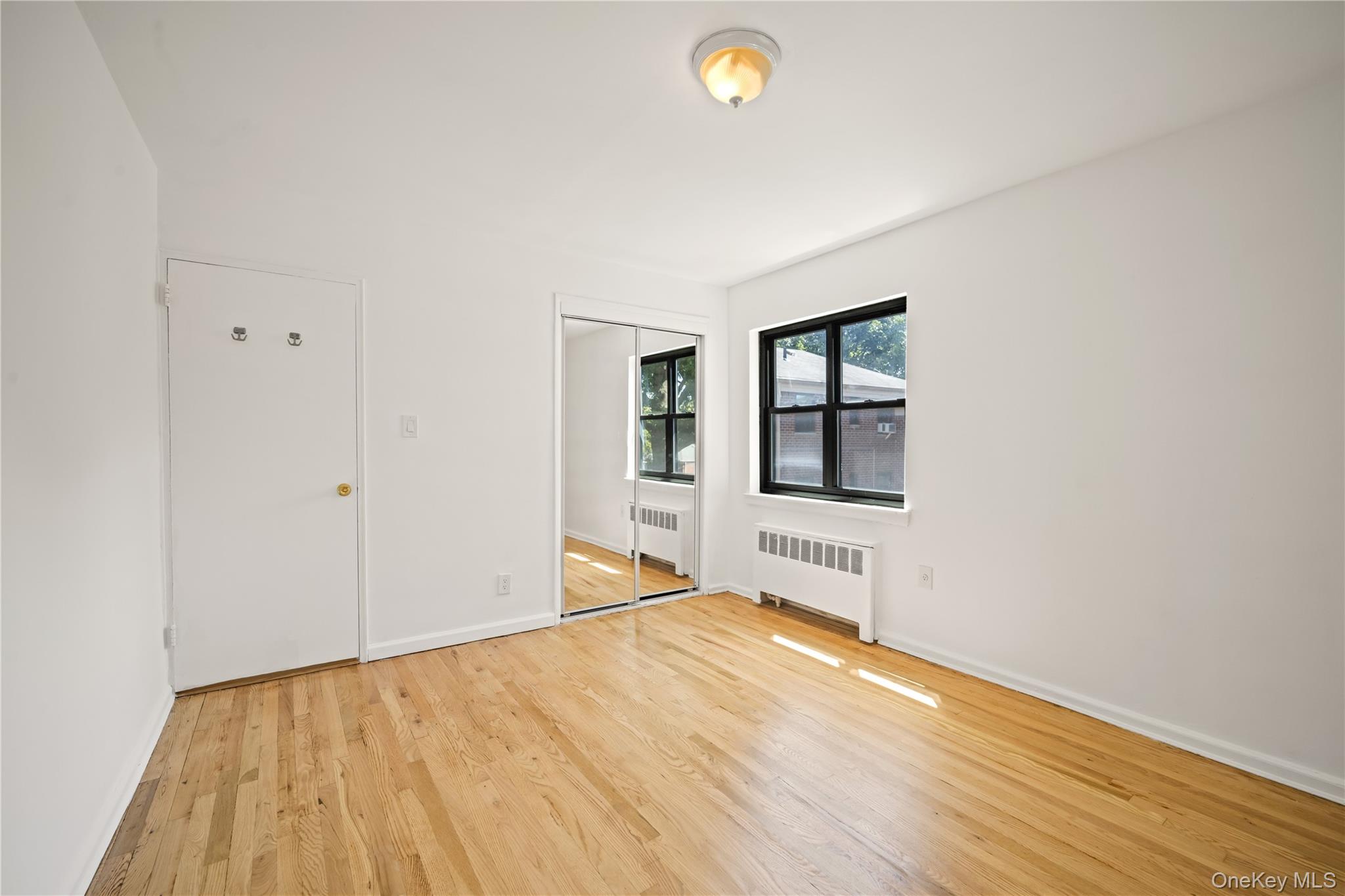 73-10 Springfield Boulevard, Unit B Queens, NY 11364 - Photo 8 of 20 Unfurnished bedroom with light wood-style flooring, radiator, and a closet