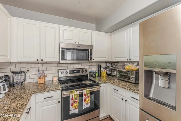 a kitchen with stainless steel appliances granite countertop a stove a sink and a white cabinets