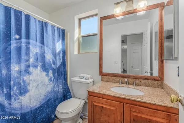 a bathroom with a granite countertop toilet a sink a mirror and a shower