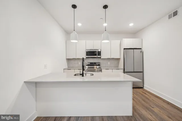 a kitchen with kitchen island white cabinets and stainless steel appliances