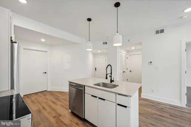 a kitchen with a sink chandelier and wooden floor