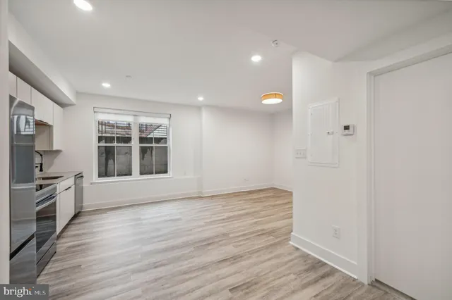 a view of an empty room with a window and wooden floor