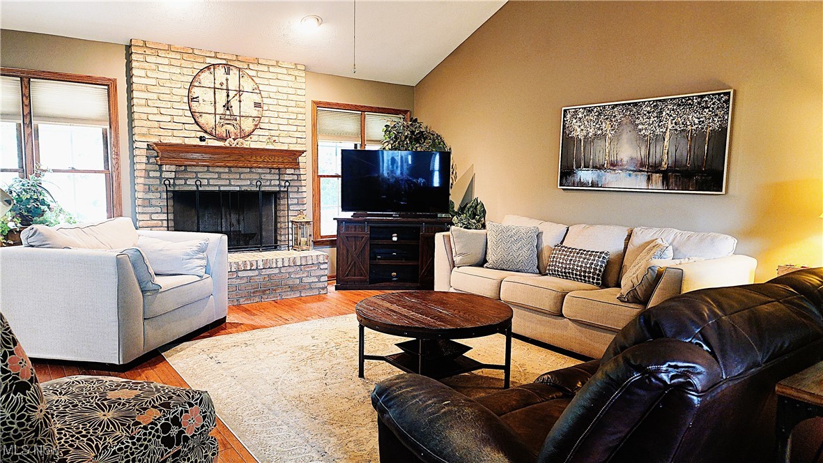 8329 Seasons Road Streetsboro, OH 44241 - Photo 13 of 35 Living room with light wood-type flooring, vaulted ceiling, brick wall, and a brick fireplace