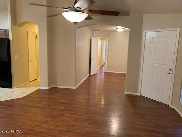 a view of an empty room with wooden floor and a ceiling fan