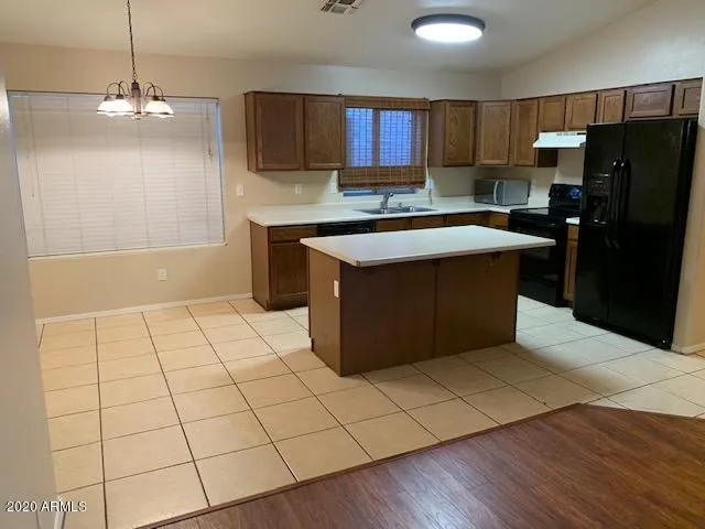 a kitchen with stainless steel appliances a sink a stove a refrigerator cabinets and a dining table