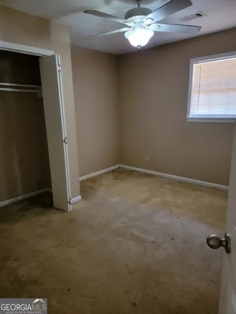en empty room with windows and chandelier fan