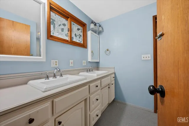 a bathroom with a granite countertop double vanity sink a mirror and a bathtub