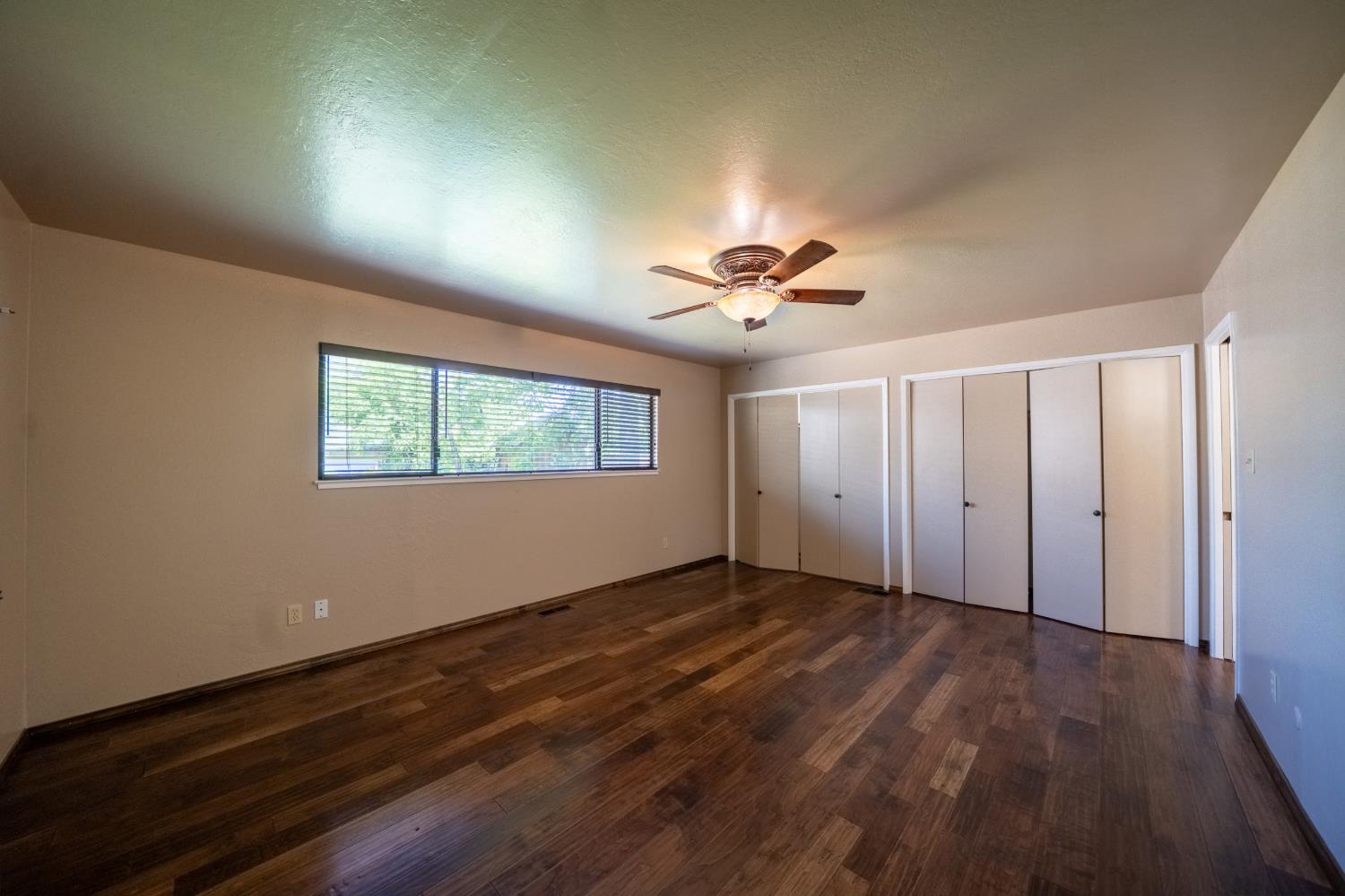118 Main Street Murphys, CA 95247 - Photo 22 of 47 an empty room with wooden floor chandelier fan and windows