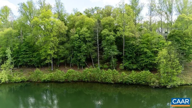 a view of a lake with a yard and trees in the background