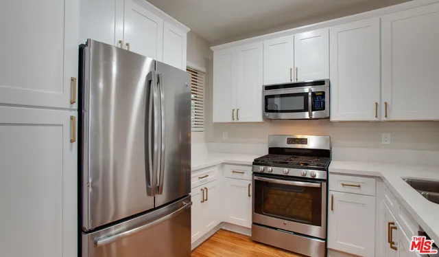 a kitchen with stainless steel appliances white cabinets white stove and a refrigerator with wooden floor