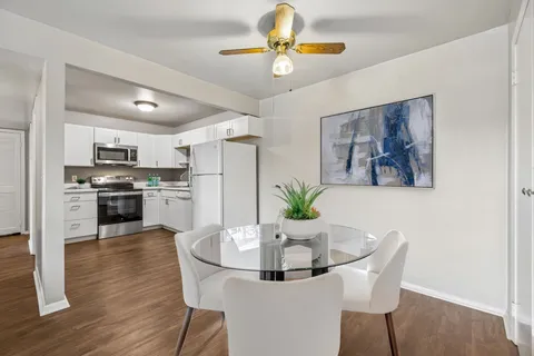 a kitchen with stainless steel appliances a dining table chairs and refrigerator