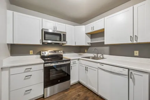 a kitchen with white cabinets stainless steel appliances and sink
