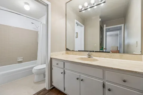 a bathroom with a granite countertop sink a toilet and a large mirror