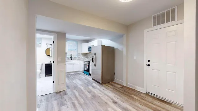 a view of a kitchen with refrigerator and wooden floor