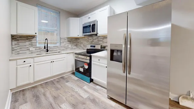 a kitchen with white cabinets stainless steel appliances and a sink