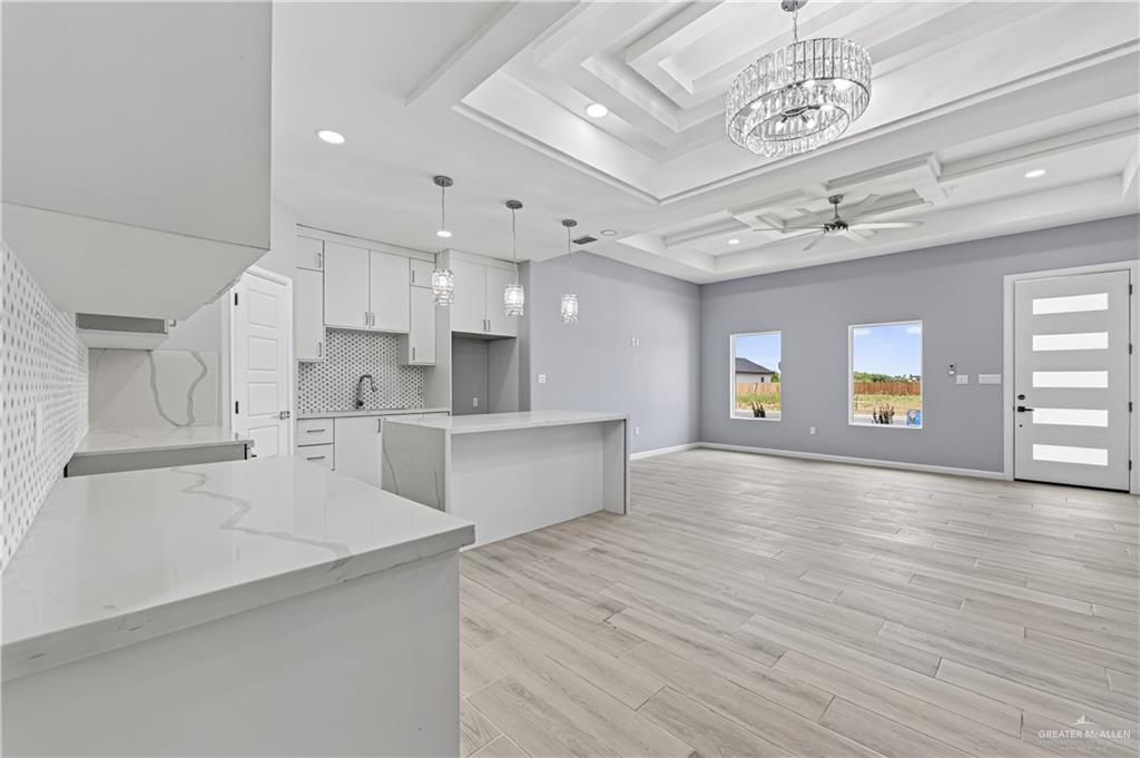 450 Sandy Road Donna, TX 78537 - Photo 6 of 15 Tray ceiling with tiered molding and recessed lighting, chandelier lighting, wood-finish flooring, two large windows, and a modern entry door