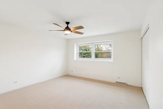 an empty room with a window and a fan
