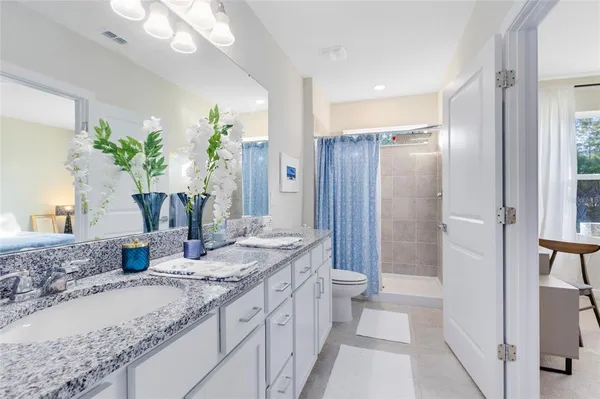 a bathroom with a granite countertop sink a toilet and shower