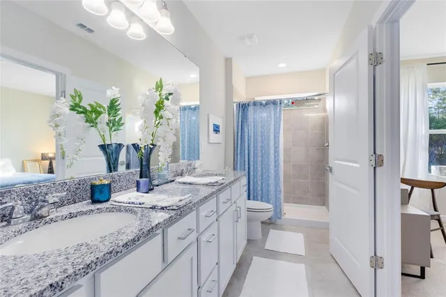 a bathroom with a granite countertop sink a toilet and shower