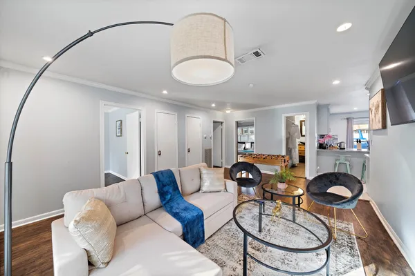a living room with furniture a flat screen tv and a refrigerator