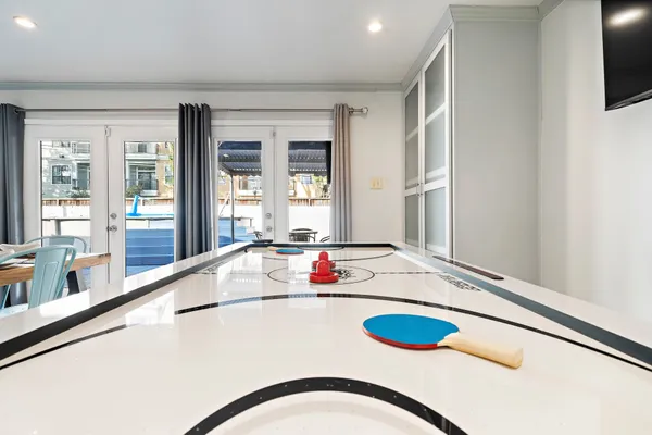 a living room with pool table flat screen tv and windows
