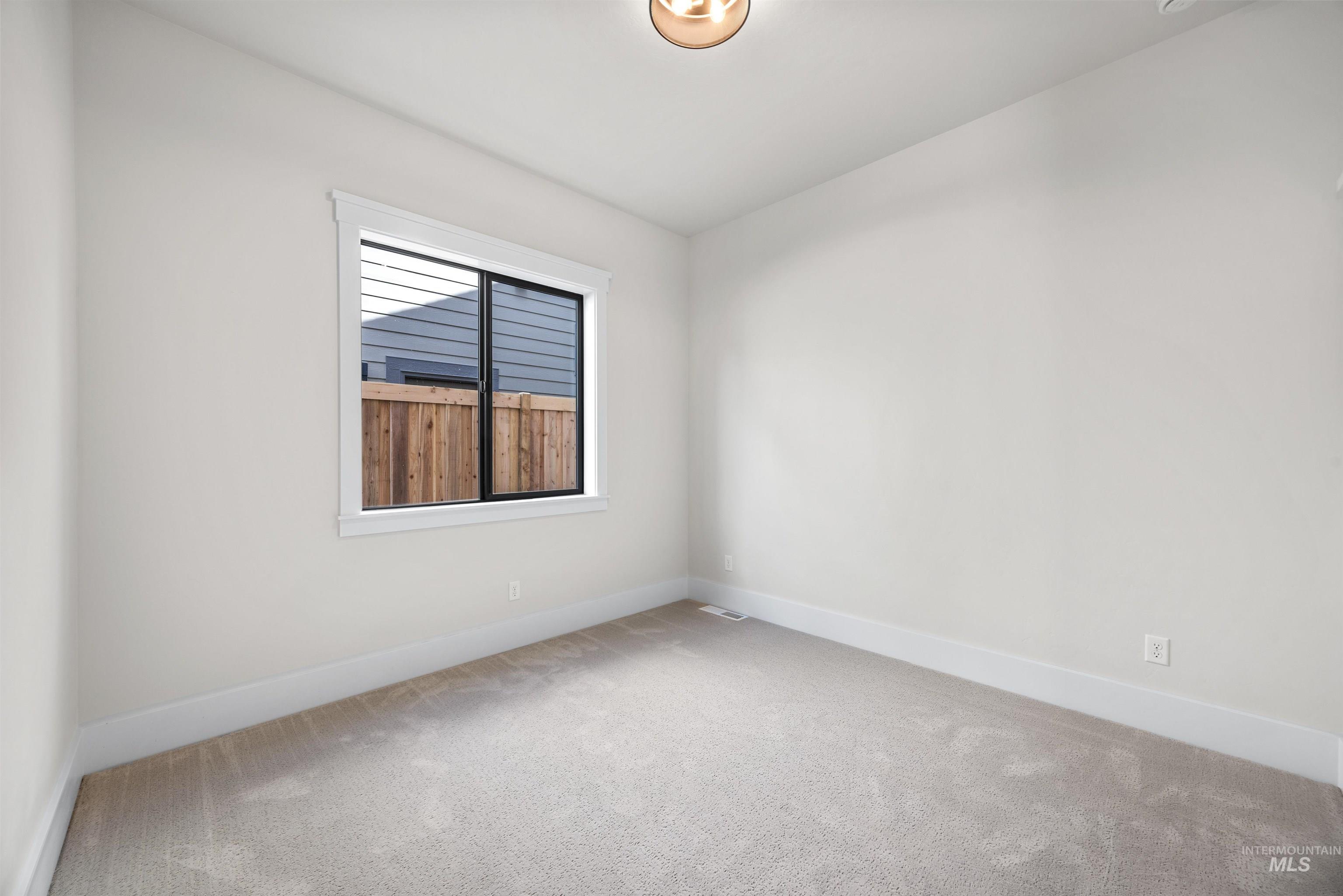 Neutral wall paint, plush carpeting, trim work, and a contemporary light fixture