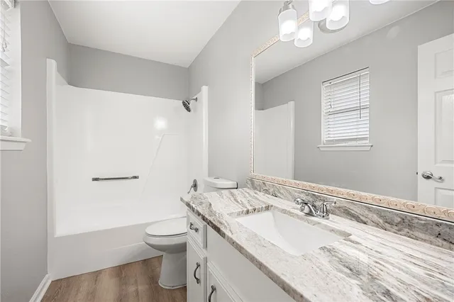 a bathroom with a granite countertop double vanity sink a mirror and a toilet