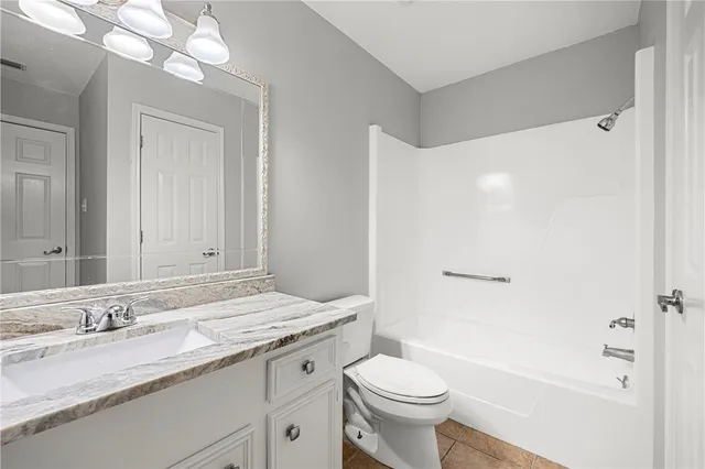a bathroom with a granite countertop sink a toilet and shower