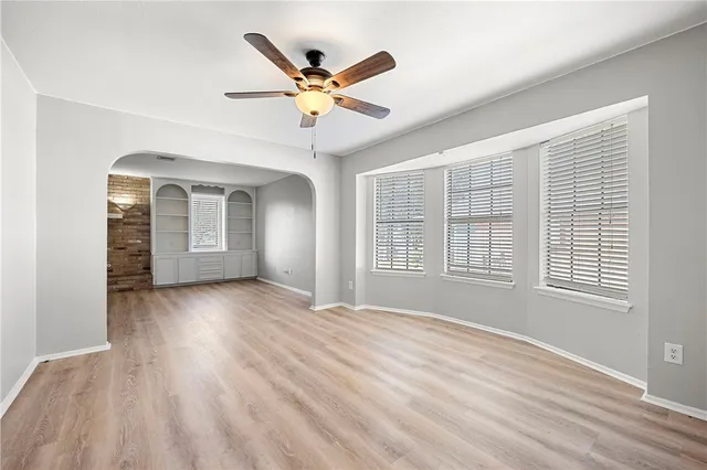 a view of an empty room with a window and wooden floor