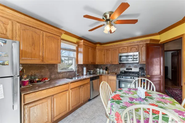a kitchen with stainless steel appliances a sink a stove a dining table chairs and a refrigerator