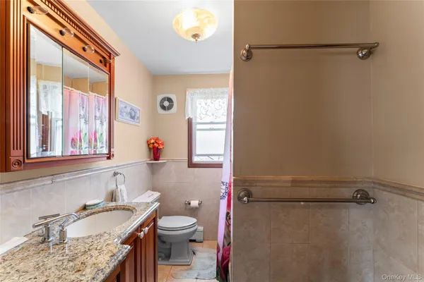 a bathroom with a granite countertop sink mirror vanity and toilet