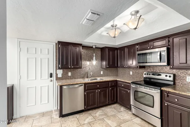 a kitchen with stainless steel appliances granite countertop a sink stove and refrigerator
