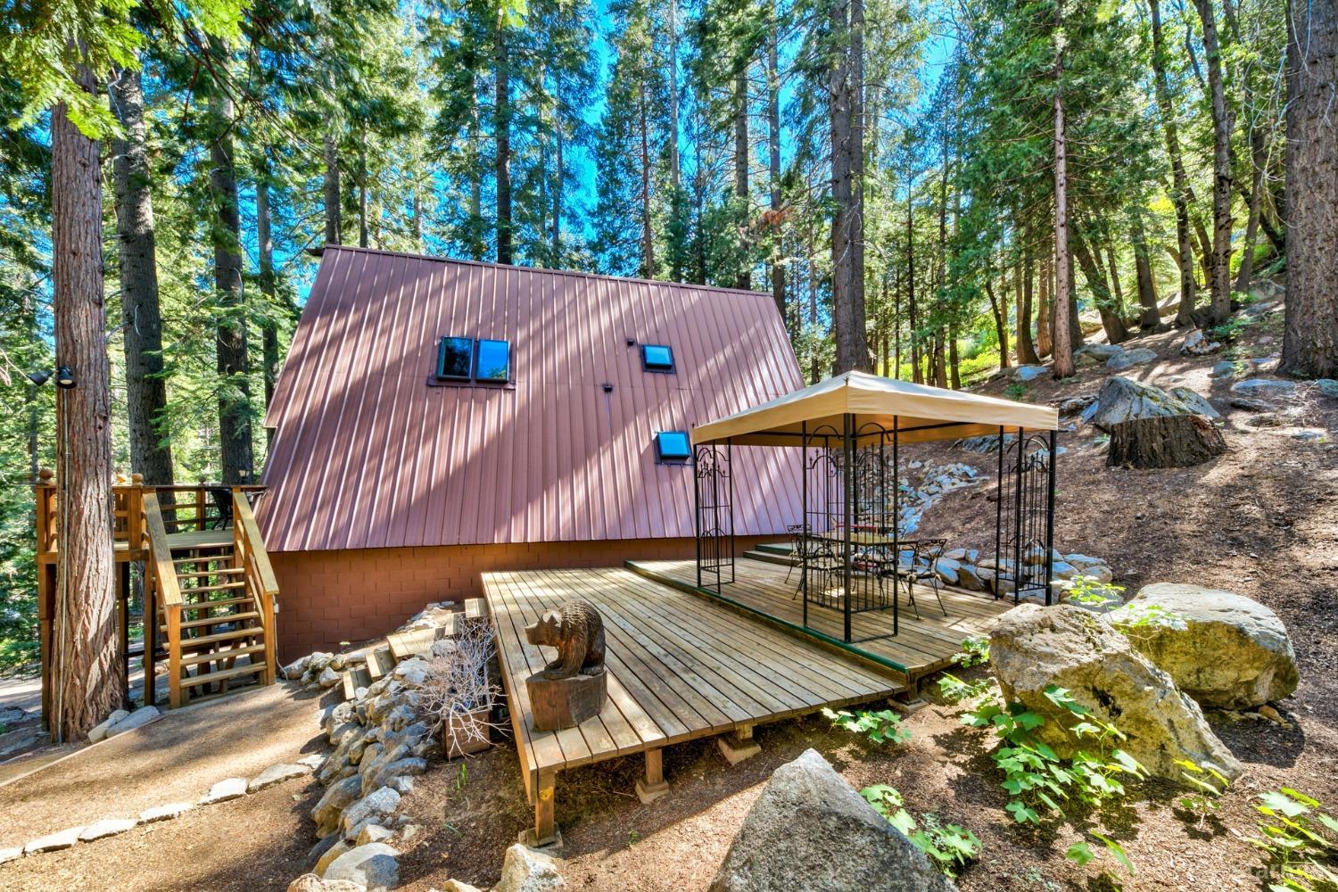 1085 Cooks Spur Road Twin Bridges, CA 95735 - Photo 5 of 30 a view of a patio with table and chairs under an umbrella with large trees