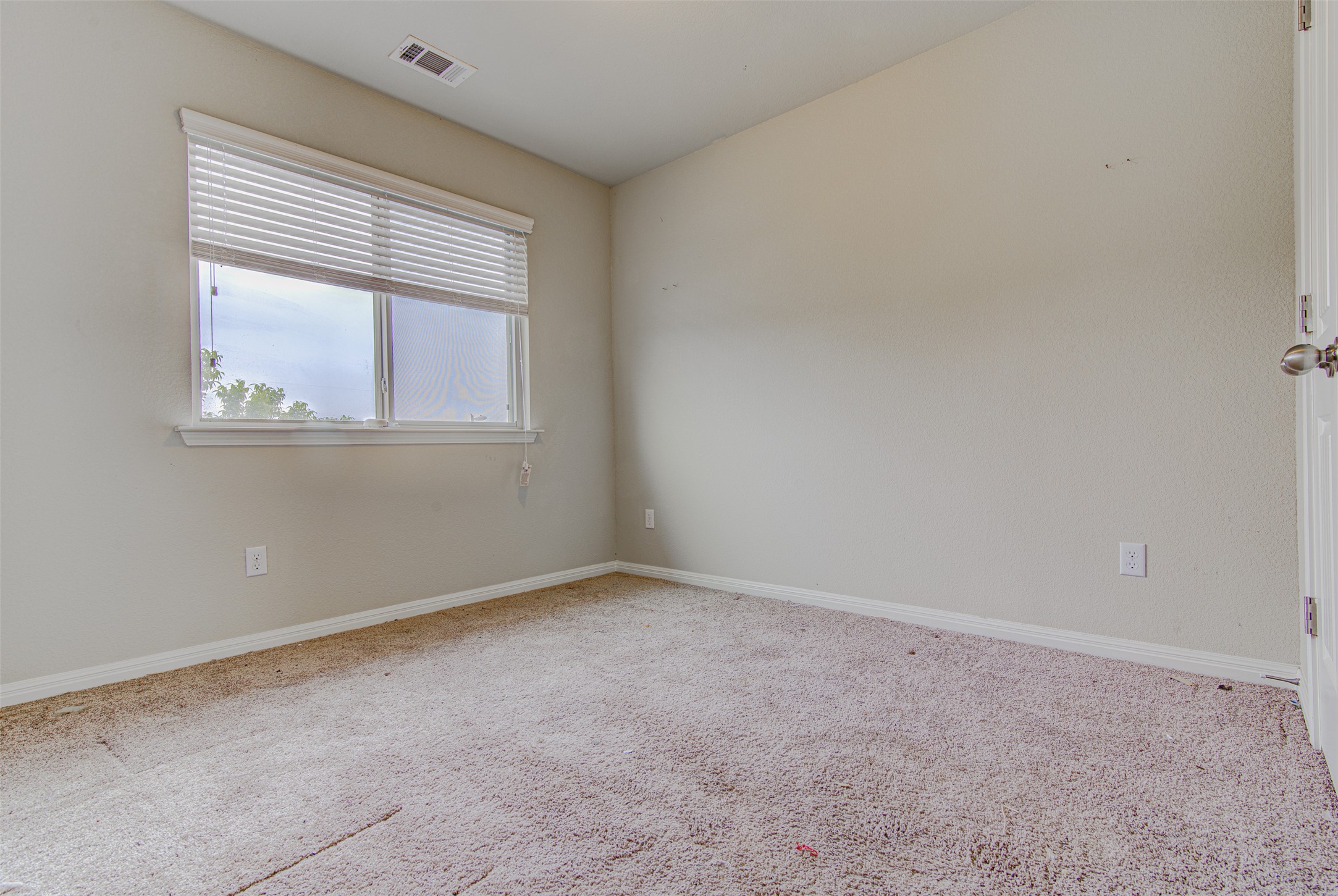 4527 Kind Way, Unit 231 Austin, TX 78725 - Photo 11 of 18 Carpeted interior space featuring a window with horizontal blinds, neutral wall paint, white baseboards, and an overhead air vent