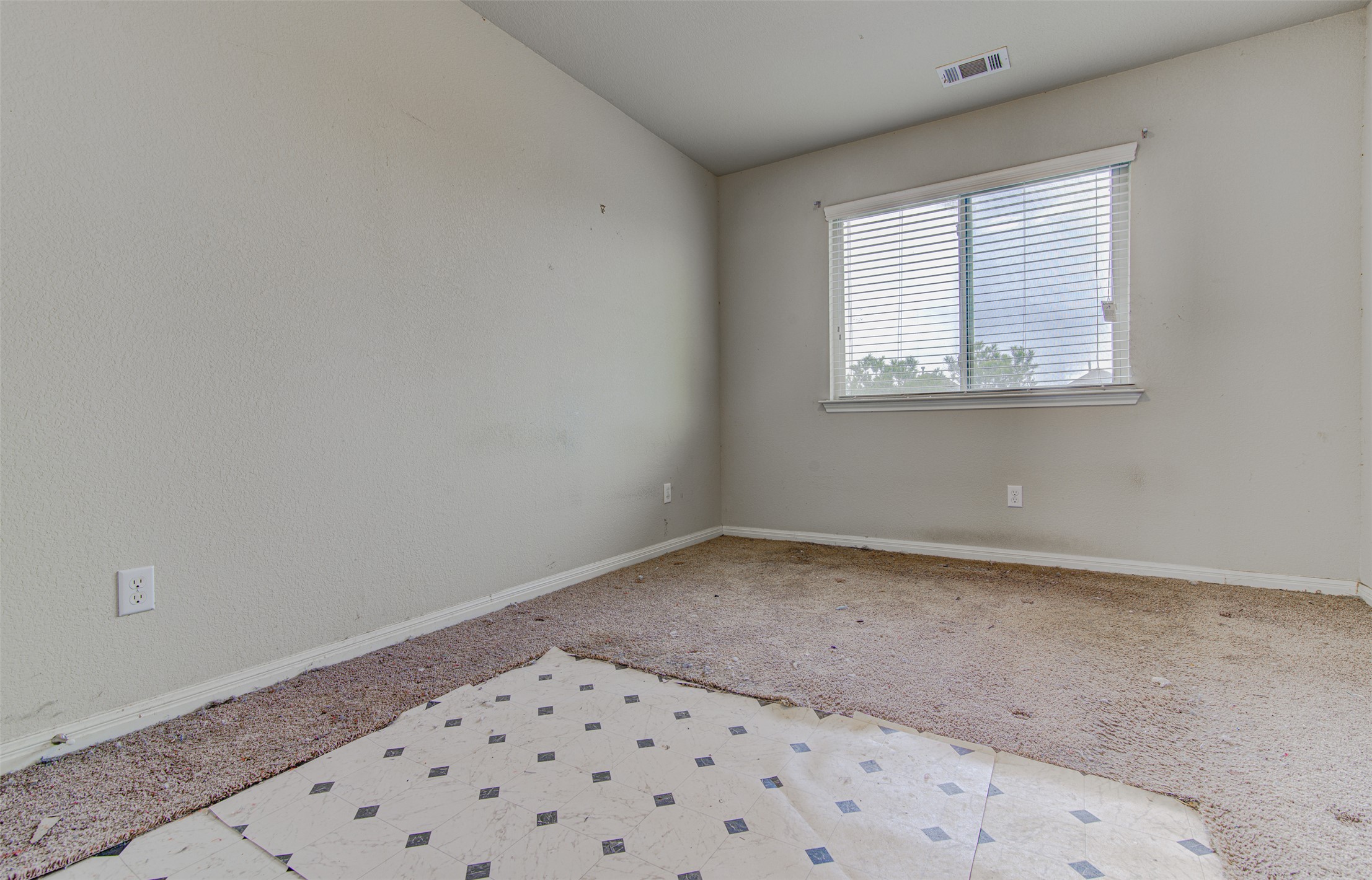 4527 Kind Way, Unit 231 Austin, TX 78725 - Photo 12 of 18 Room featuring a window with blinds, light-toned walls, and mixed flooring with carpeting and patterned vinyl