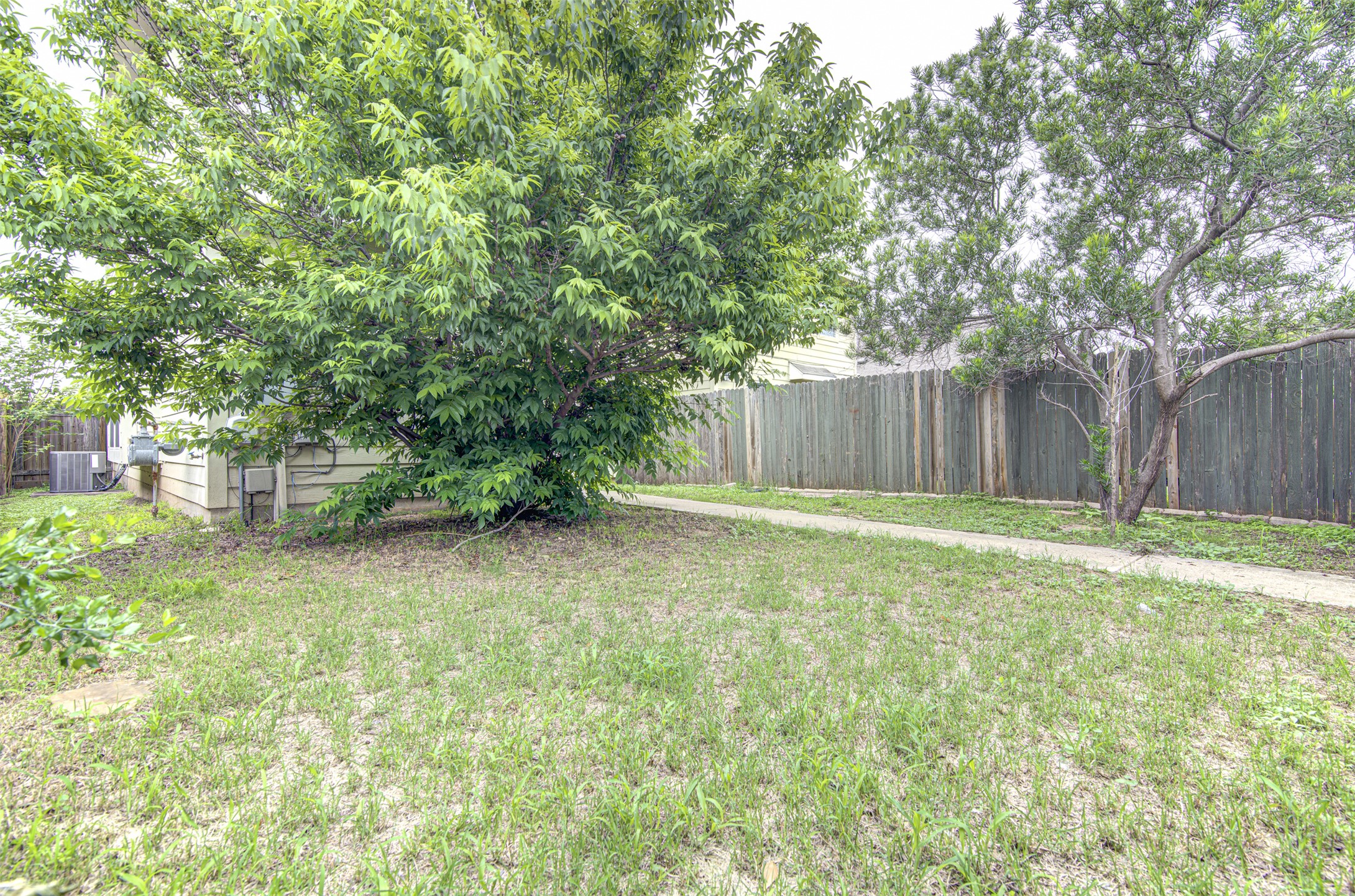 4527 Kind Way, Unit 231 Austin, TX 78725 - Photo 15 of 18 Expansive grass lawn with mature trees and a concrete pathway