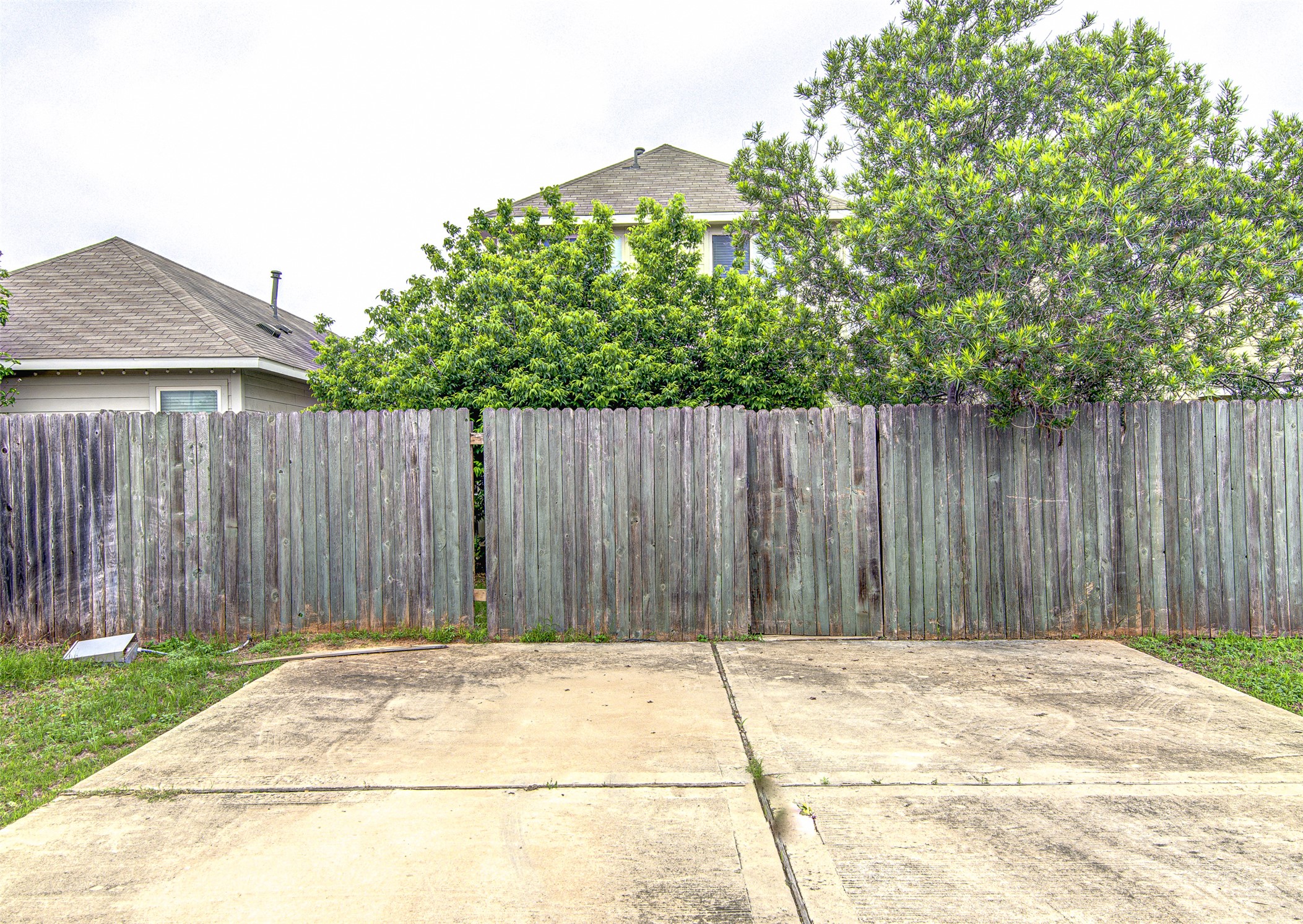 4527 Kind Way, Unit 231 Austin, TX 78725 - Photo 18 of 18 Concrete patio area featuring a wood privacy fence and surrounding green landscaping