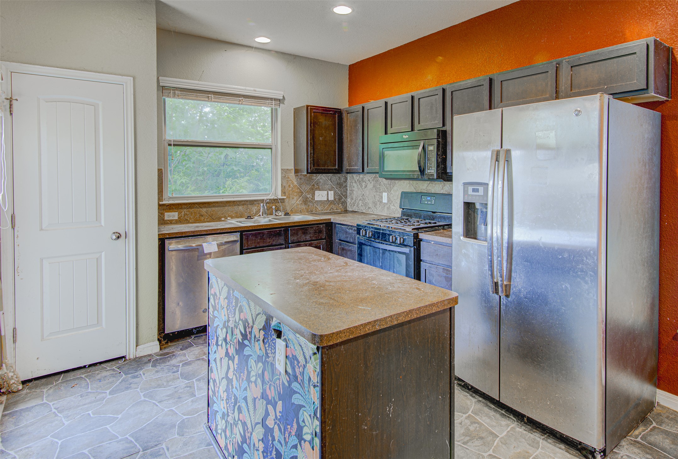 4527 Kind Way, Unit 231 Austin, TX 78725 - Photo 7 of 18 Kitchen featuring an island, stone-finish tile flooring, dark cabinetry, and stainless steel appliances