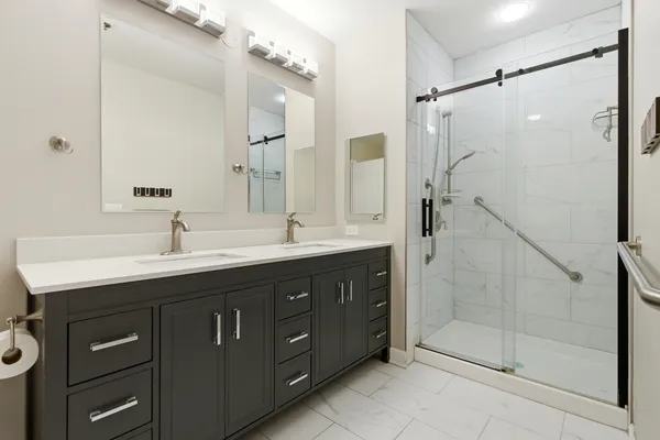 a bathroom with a double vanity sink mirror and shower