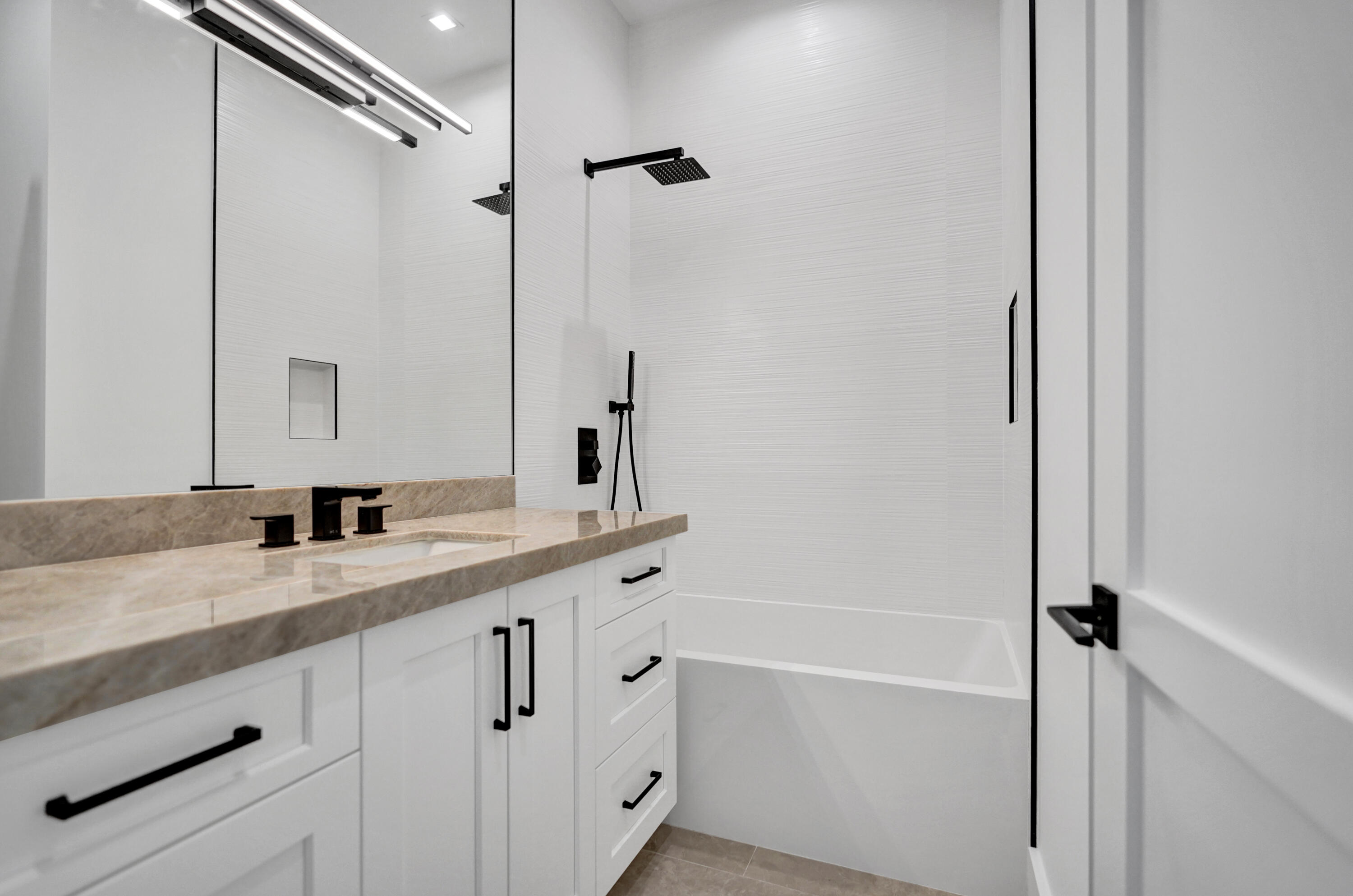 4451 Northeast 27th Terrace Lighthouse Point, FL 33064 - Photo 23 of 38 a bathroom with a granite countertop sink a mirror and a bathtub