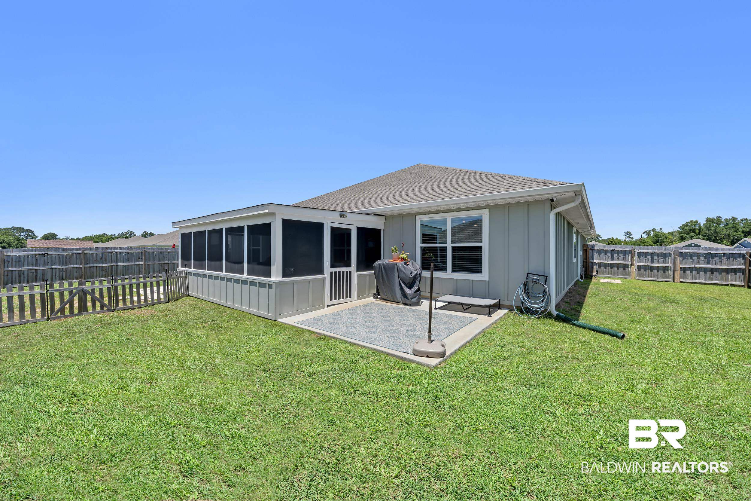 24271 Ringneck Loop Elberta, AL 36530 - Photo 33 of 44 Rear exterior featuring a screened-in porch, concrete patio, and extensive lawn