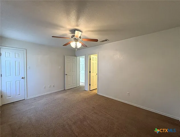 an empty room with windows and fan
