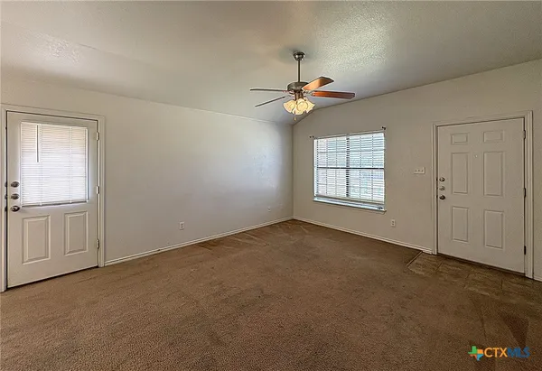 an empty room with windows and fan